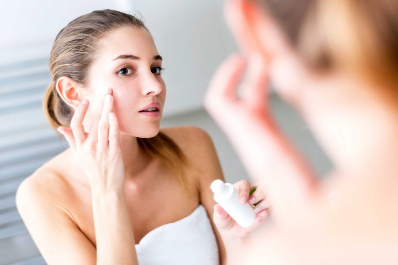 Fille se frotte le visage en regardant dans le miroir