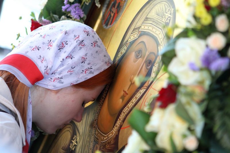 Fille s'incline devant l'icône de Notre-Dame