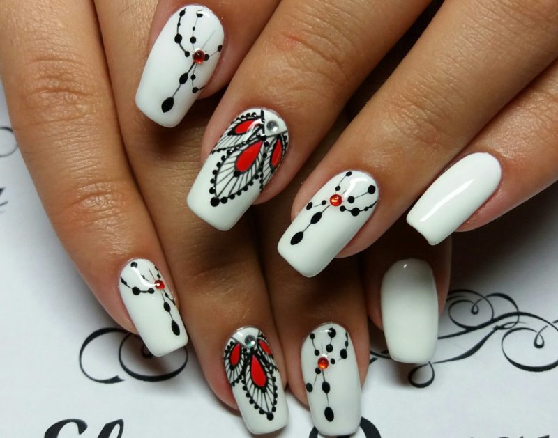 Ongles blancs à motifs noirs et rouges