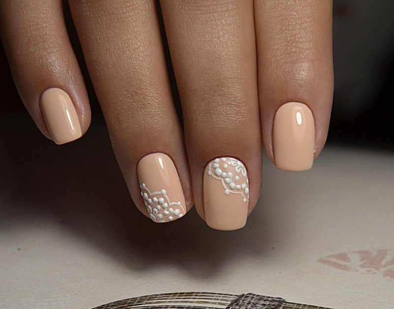 Manucure beige orangé avec dentelle blanche.