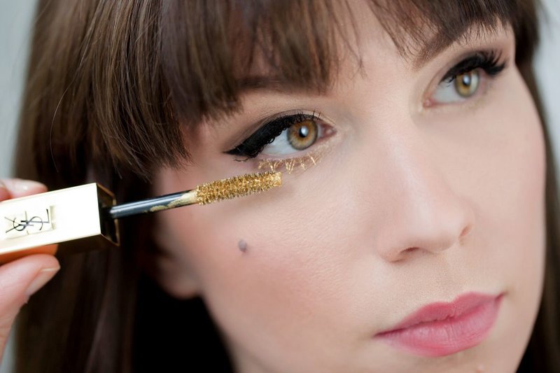 Maquillage avec des flèches et du mascara doré sur les cils inférieurs