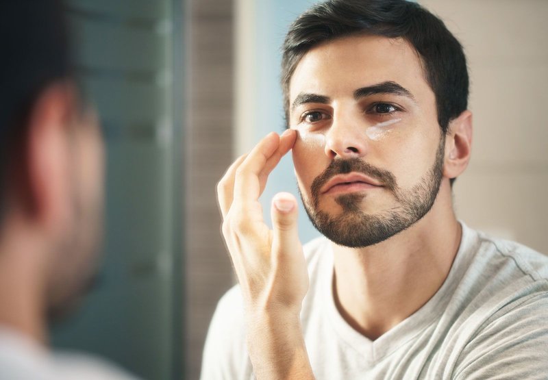 Un homme applique de la crème sur son visage