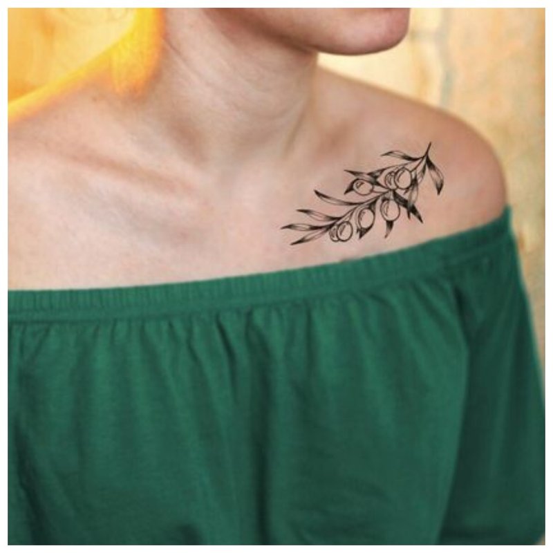 Ang tattoo sprig ng isang batang babae sa collarbone