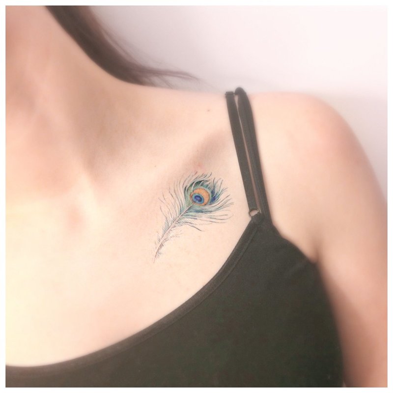 Orihinal na maliwanag na feather tattoo sa clavicle