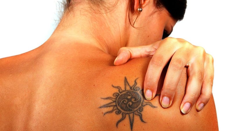 Fille avec un tatouage après le bronzage